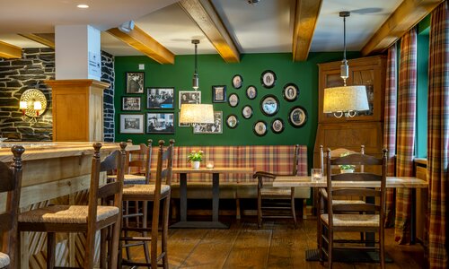 Blick in eine urige Restaurantstube mit alten Holzmöbeln und einer grünen Wand.