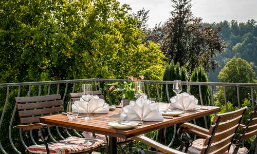 Ein gedeckter Tisch mit Servietten und Weingläsern auf der Terrasse an einem sonnigen Tag.