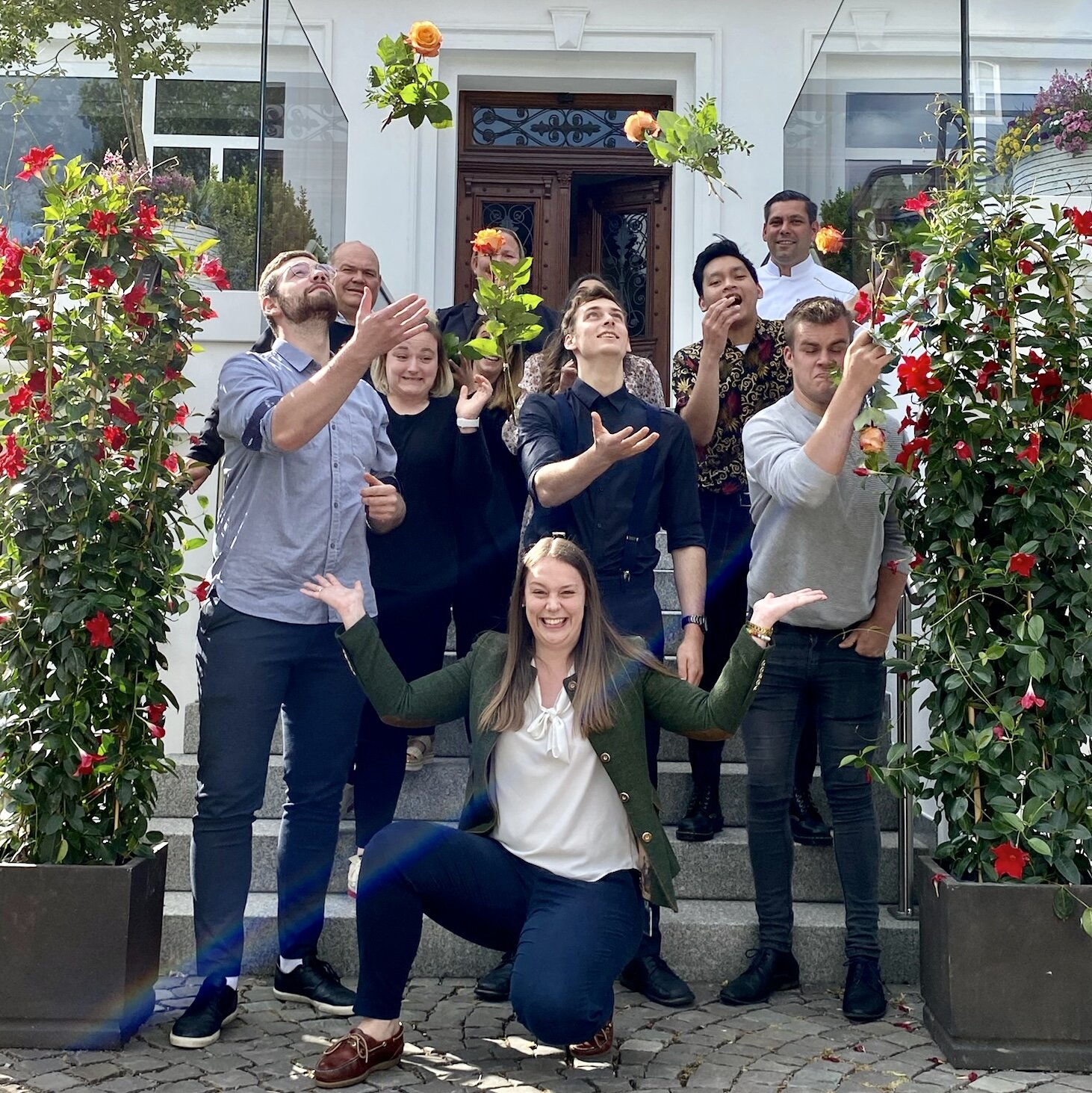Eine Gruppe junger Auszubildende wirft Rosen in die Luft und dankt dem Top Arbeitgeber Hotel Deimann.