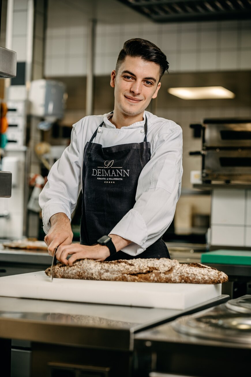 Junger Koch schneidet ein Baguette in der Küche während seiner Ausbildung in Schmallenberg im Sauerland.