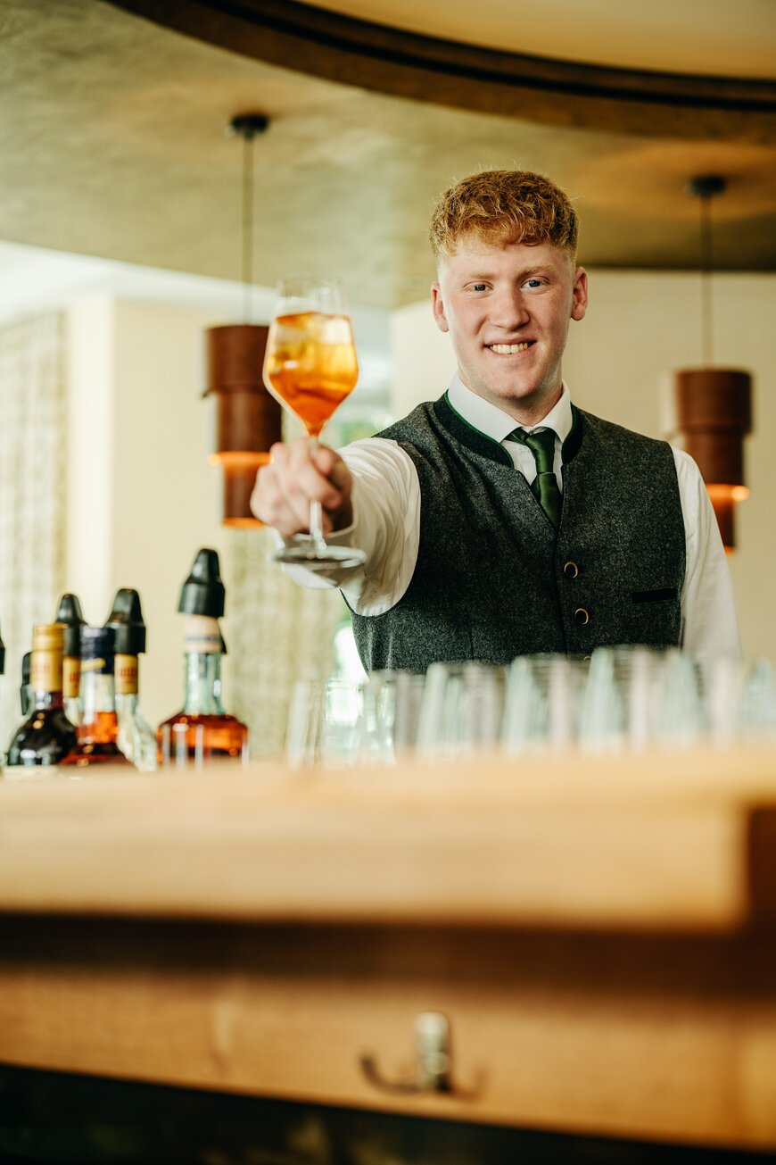 Barkeeper hinter der Bar und einem Getränk in der Hand während seiner Ausbildung in Schmallenberg im Sauerland
